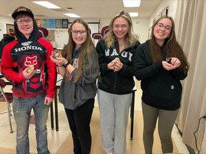 four high school students smile at the camera with chicks in their hands