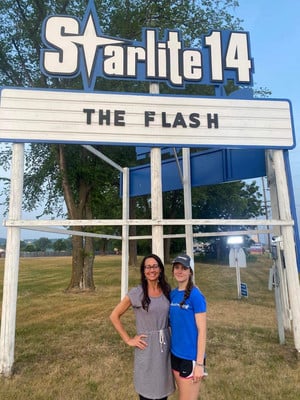 A youth apprenticeship student stands in front of the Starlite 14 theatre sign with her supervisor
