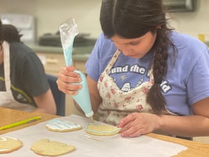 a student decorates a cookie in a food science class